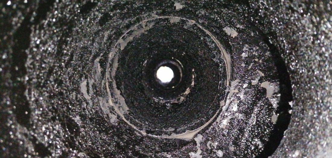 Intérieur d’un conduit de cheminée fortement encrassé par une épaisse couche de bistre noir.